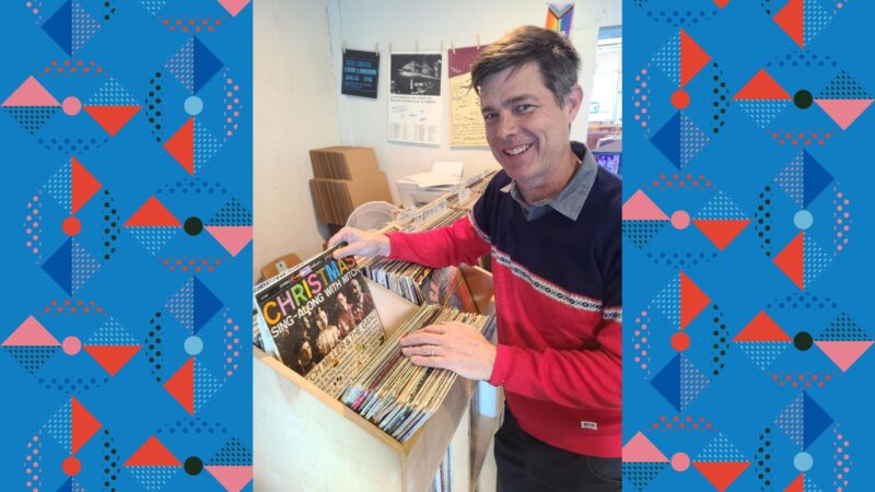 Larry Morrisey standing in a record store flipping through a box of old Christmas records.