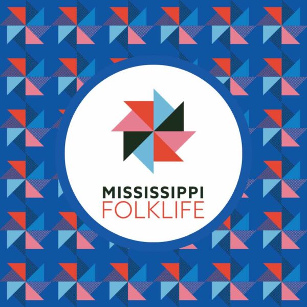 The Mississippi folklife pattern sits on a blue background with the logo stamped multiple times across and up and down with a white circle around the logo. The logo features a pinwheel with each triangle alternating colors between black, a redish orange, and a light blue color. The text below the pinwheel image says 'Mississippi' in a black color and 'Folklife' in a red color.